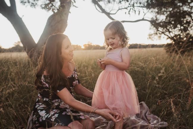 Pregnant mother fixing daughter's dress during Perth maternity photography session during golden hour at Perry's Paddock
