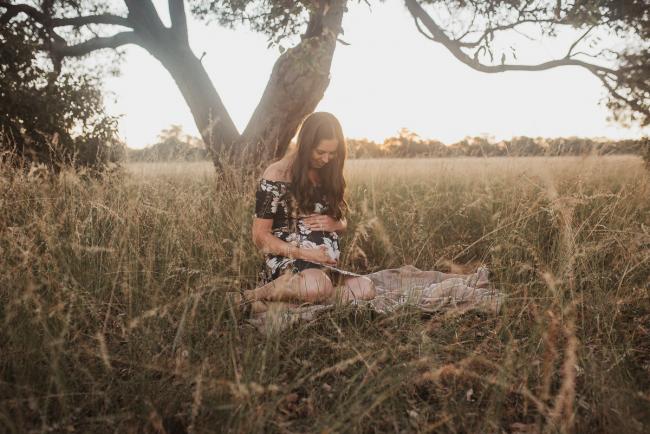 Pregnant woman sitting on blanket during Perth maternity photography session during golden hour at Perry's Paddock
