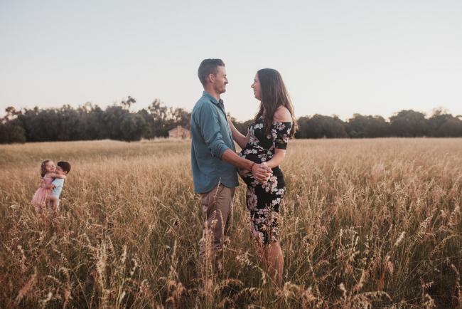 Mother and father dancing as son and daughter dance behind them during Perth maternity photography session during golden hour at Perry's Paddock
