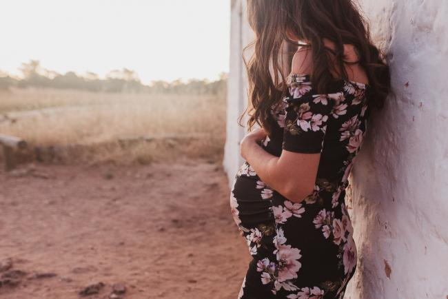 Pregnant woman leaning against white wall during Perth maternity photography session during golden hour at Perry's Paddock