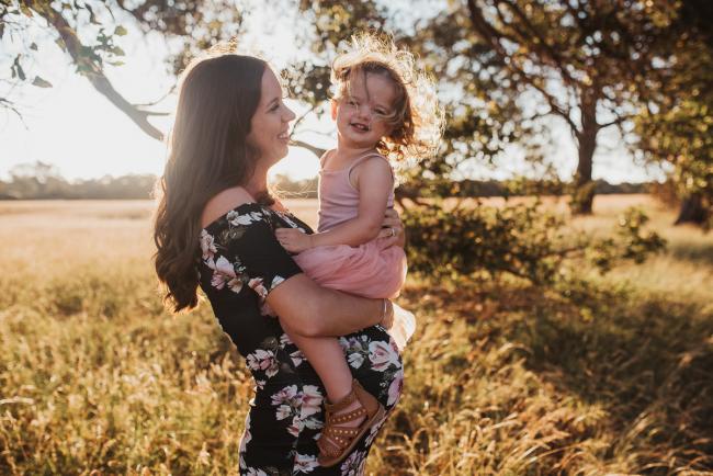 Pregnant mother holding daughter during Perth maternity photography session during golden hour at Perry's Paddock
