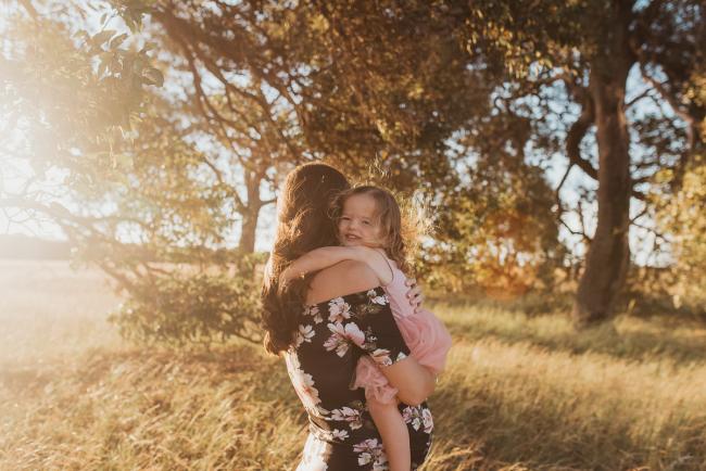Daughter cuddling pregnant mother during Perth maternity photography session during golden hour at Perry's Paddock