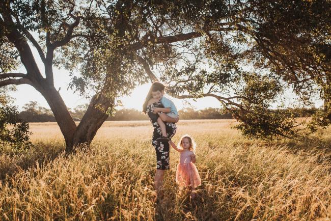 Pregnant mother holding son with daughter standing next to them during Perth maternity photography session during golden hour at Perry's Paddock