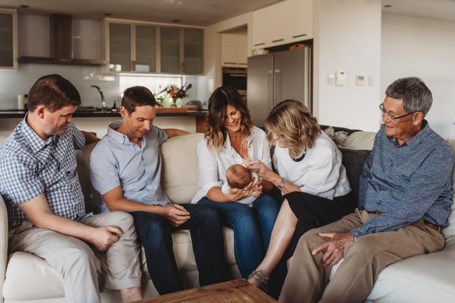Family of parents, grandparents and uncle on couch with newborn baby with Perth newborn lifestyle photographer