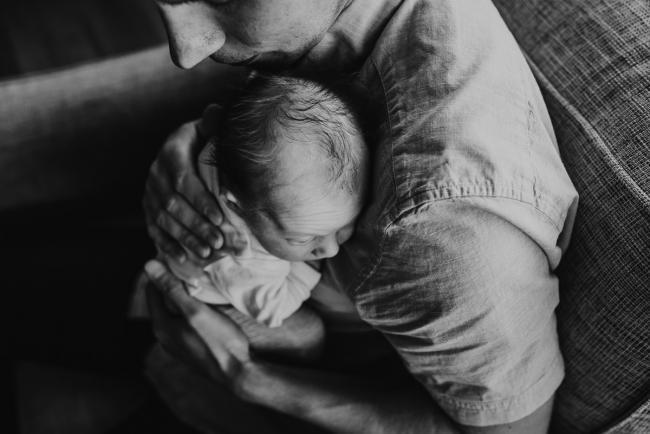 Newborn-Lifestyle-Photographer-Perth-10-of-50 black and white top down image of newborn baby resting on dad's shoulder during Perth lifestyle newborn photography session