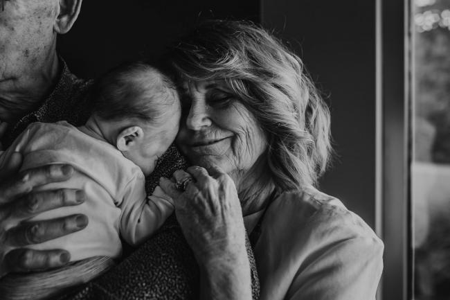Newborn-Lifestyle-Photographer-Perth-18-of-50 black and white image of grandmother cuddling into newborn baby being held by grandfather during Perth lifestyle newborn photography session