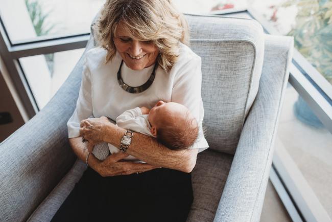Newborn-Lifestyle-Photographer-Perth-19-of-50 grandmother holding newborn baby on chair during Perth lifestyle newborn photography session