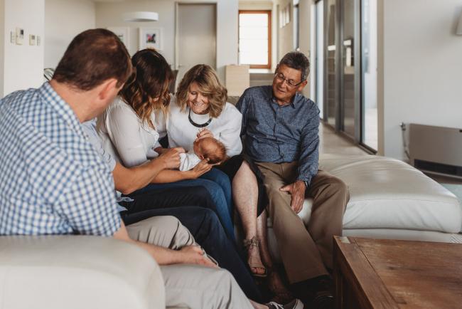 Newborn-Lifestyle-Photographer-Perth-2-of-50 Family sitting on a couch looking at newborn baby during Perth lifestyle newborn photography session