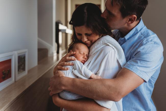 Father kissing mother as mother kisses newborn baby during Perth lifestyle newborn photography session