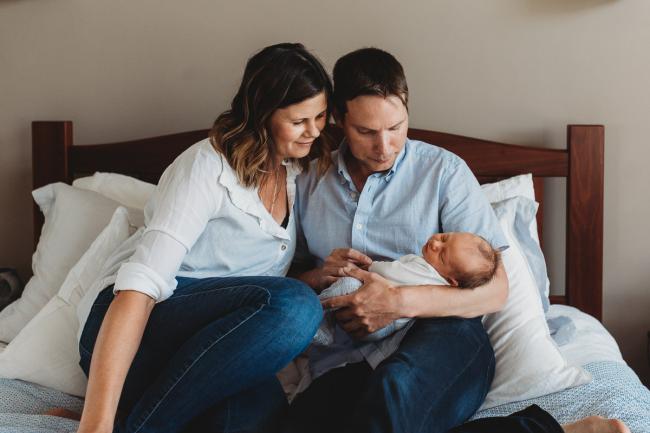Newborn-Lifestyle-Photographer-Perth-27-of-50 Mother and father holding newborn baby on the bed during Perth lifestyle newborn photography session