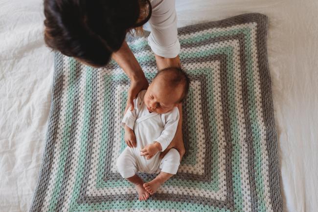mother placing newborn baby on blanket during Perth lifestyle newborn photography session