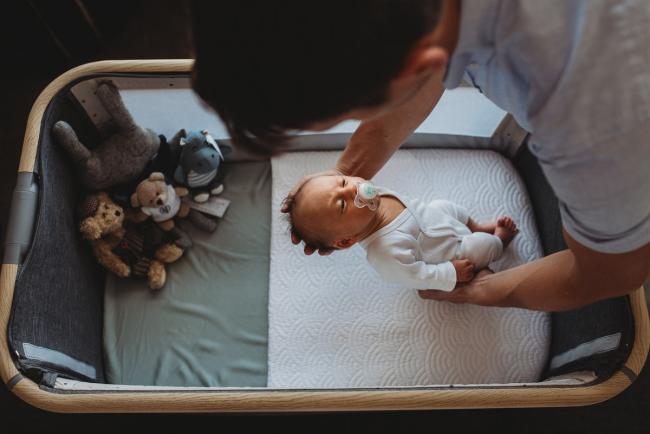 Father placing newborn baby in bassinet during Perth lifestyle newborn photography session