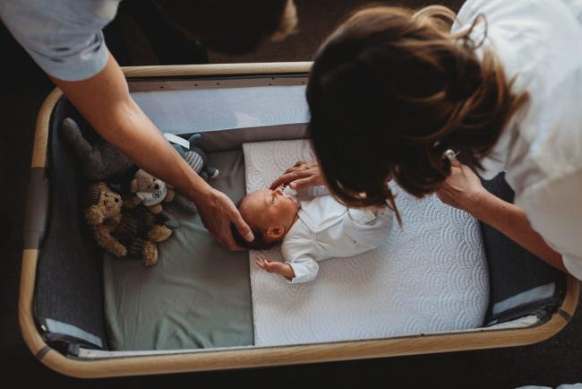 Newborn-Lifestyle-Photographer-Perth-39-of-50 Parents reaching into bassinet of newborn baby during Perth lifestyle newborn photography session