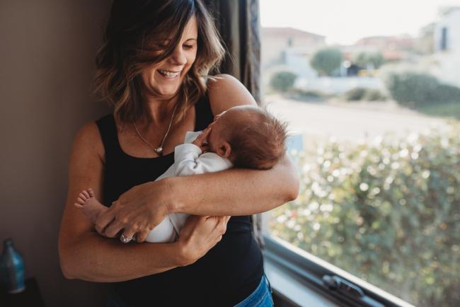 Newborn-Lifestyle-Photographer-Perth-42-of-50 Mother smiling as she holds newborn baby during Perth lifestyle newborn photography session