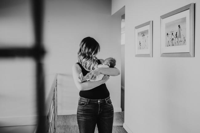 Newborn-Lifestyle-Photographer-Perth-46-of-50 black and white image of mother holding newborn baby in hallway during Perth lifestyle newborn photography session