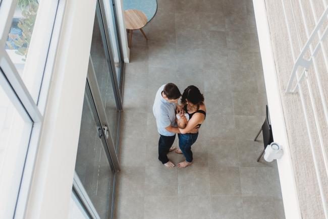 top down image of parents at bottom of stairs facing each other with newborn baby with Perth newborn lifestyle photographer