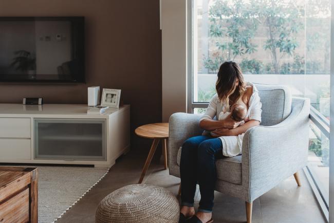Newborn-Lifestyle-Photographer-Perth-6-of-50 mother breastfeeding newborn baby on a chair by the window during Perth lifestyle newborn photography session