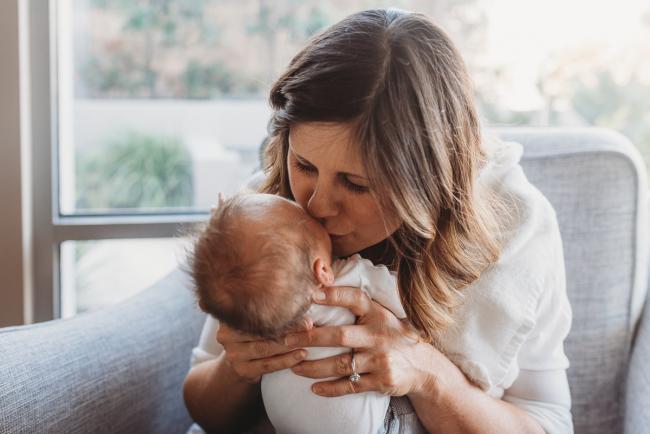 mother kissing newborn baby during Perth lifestyle newborn photography session
