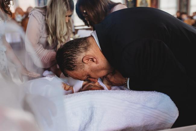Perth-Events-Photographer-Christening-11-of-25 Grandfather bending down to kiss granddaughter at baptism at Macedonian Orthodox Church with Perth events photographer