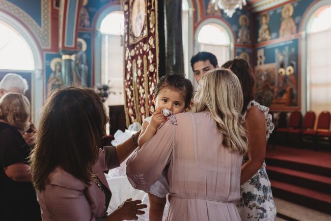 Perth-Events-Photographer-Christening-12-of-25 Little girl looking over the shoulder of her mother at baptism at Macedonian Orthodox Church with Perth events photographer