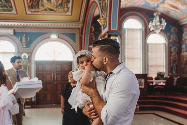 Perth-Events-Photographer-Christening-24-of-25 Man kissing little girl at baptism at Macedonian Orthodox Church with Perth events photographer