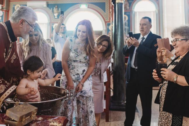 Perth-Events-Photographer-Christening-9-of-25 People watching little girl being baptised in water at baptism at Macedonian Orthodox Church with Perth events photographer