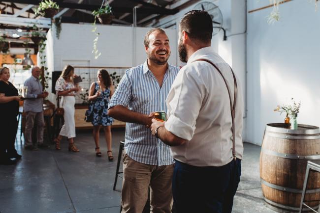 Men smiling and greeting each other during a party at Cleaver St Event Space with Perth events photographer