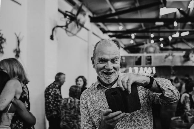 black and white image of man taking photo with his phone during a party at Cleaver St Event Space with Perth events photographer