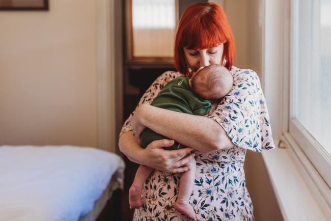 Mother kissing newborn baby during in-home Perth newborn lifestyle photography session