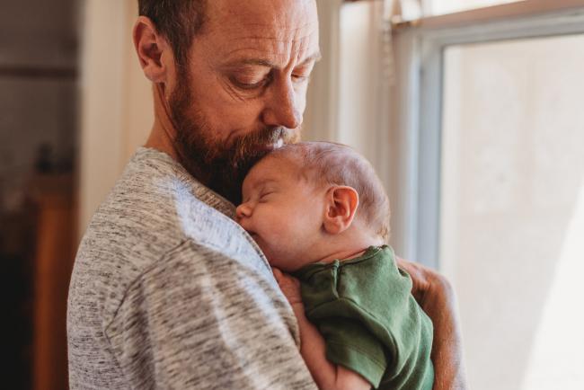 Father holding newborn baby on his shoulder with Perth newborn lifestyle photographer