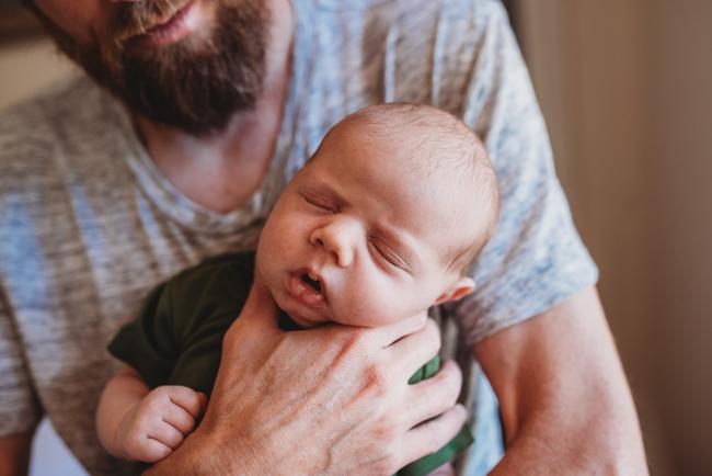 Close up of newborn baby being held by father during in-home Perth newborn lifestyle photography session