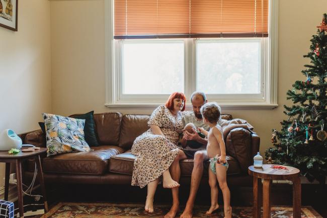 Family of four on couch during in-home Perth newborn lifestyle photography session