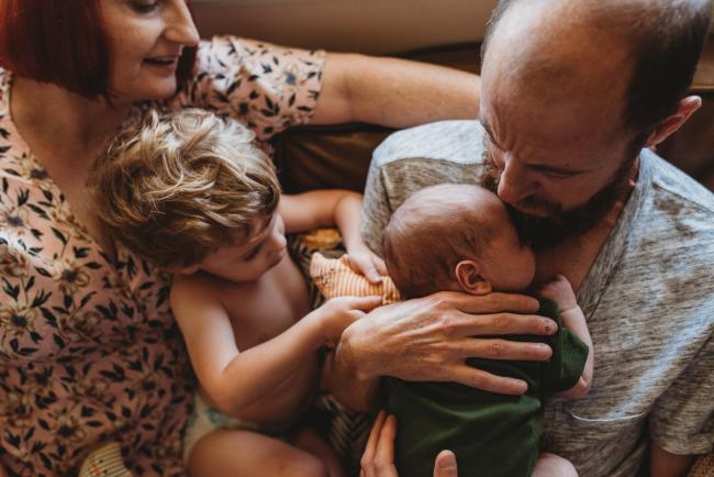 Family of four on couch during in-home Perth newborn lifestyle photography session
