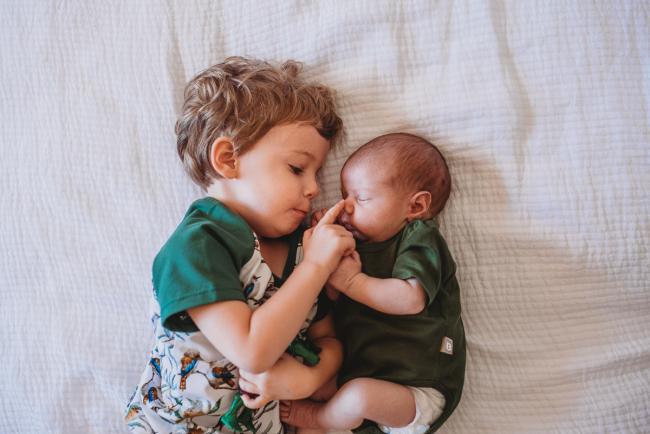Little boy touching the nose of his newborn baby brother during newborn photography Perth session