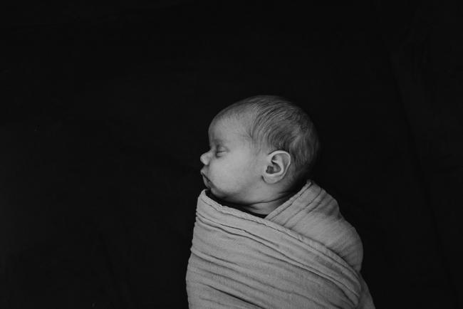 black and white image of newborn baby in wrap during in-home Perth newborn lifestyle photography session
