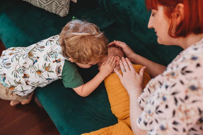 Boy and mother touching newborn baby during in-home Perth newborn lifestyle photography session