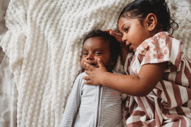 Little girl touching face of newborn baby brother with in-home Perth lifestyle newborn photographer