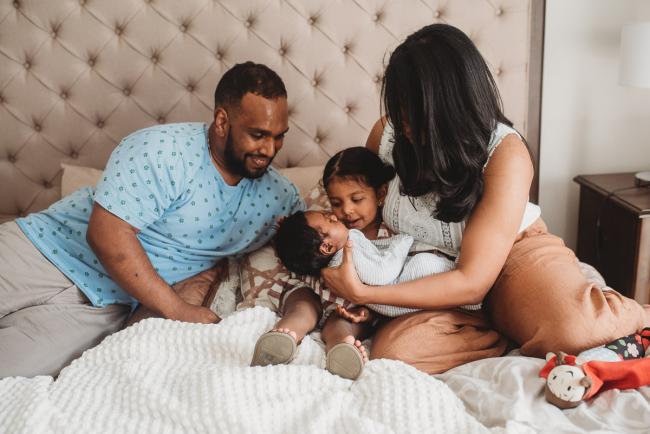 Family of four on the bed with in-home Perth lifestyle newborn photographer