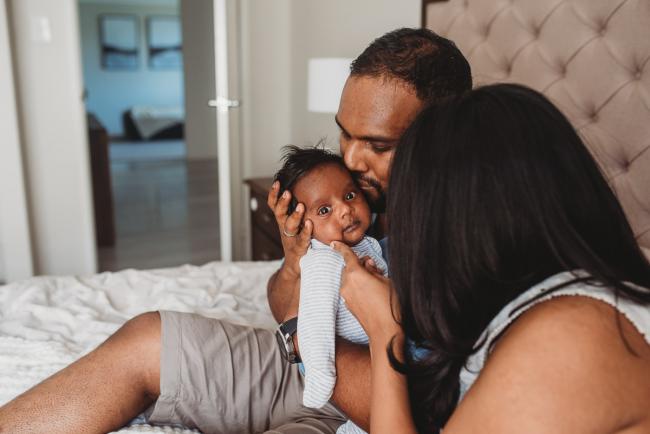 Father kissing newborn baby with in-home Perth lifestyle newborn photographer