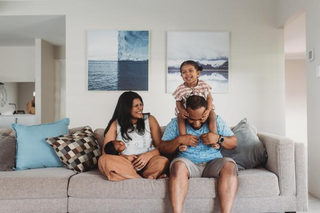 Little girl sitting on father's shoulder and mother holding newborn baby with in-home Perth lifestyle newborn photographer