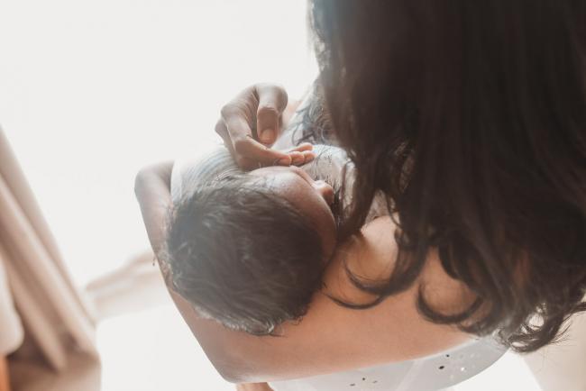 Mother touching face of newborn baby with Perth newborn photographer