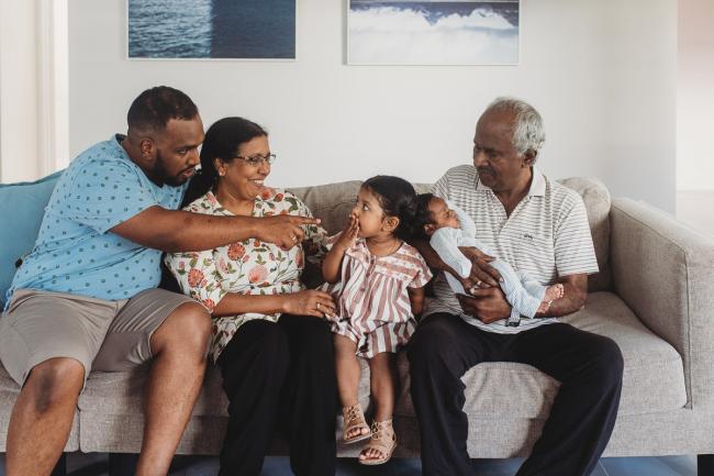 Grandparents with father and grandchildren on couch with in-home Perth lifestyle newborn photographer
