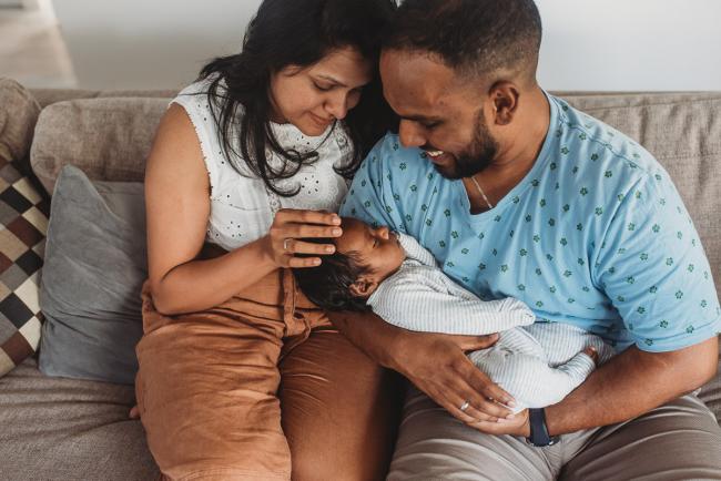 Parents holding newborn baby with in-home Perth lifestyle newborn photographer