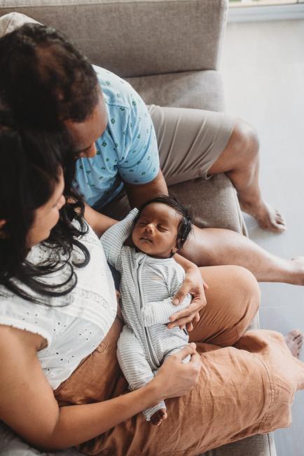 Newborn baby sleeping on lap of parents with in-home Perth lifestyle newborn photographer