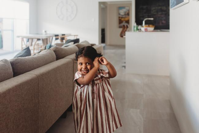 Little girl smiling and playing with her hair with in-home Perth lifestyle newborn photographer