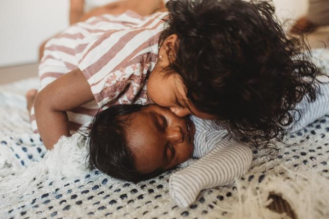Little girl kissing newborn baby brother with in-home Perth lifestyle newborn photographer