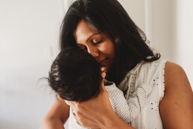 Mother kissing newborn baby with in-home Perth lifestyle newborn photographer