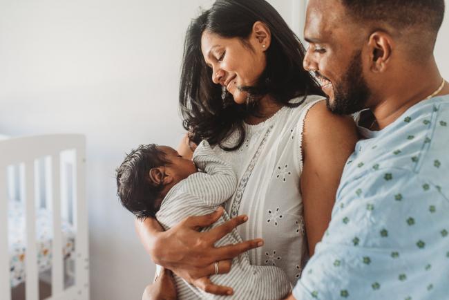 Parents smiling at newborn baby with in-home Perth lifestyle newborn photographer