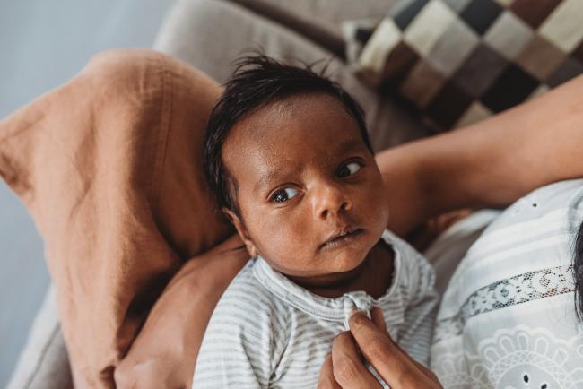 Newborn baby in mothers arms with in-home Perth lifestyle newborn photographer