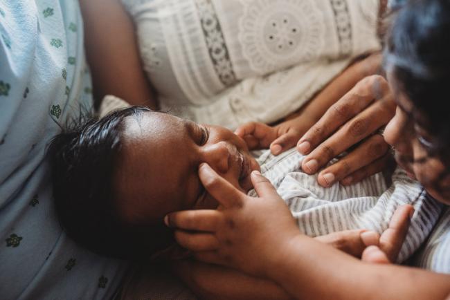 Little girl touching newborn baby's face with in-home Perth lifestyle newborn photographer